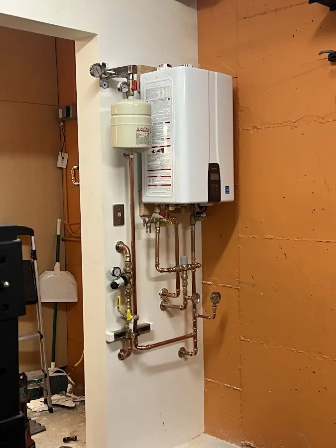 Plumbing technician inspecting water heater connections in University Heights